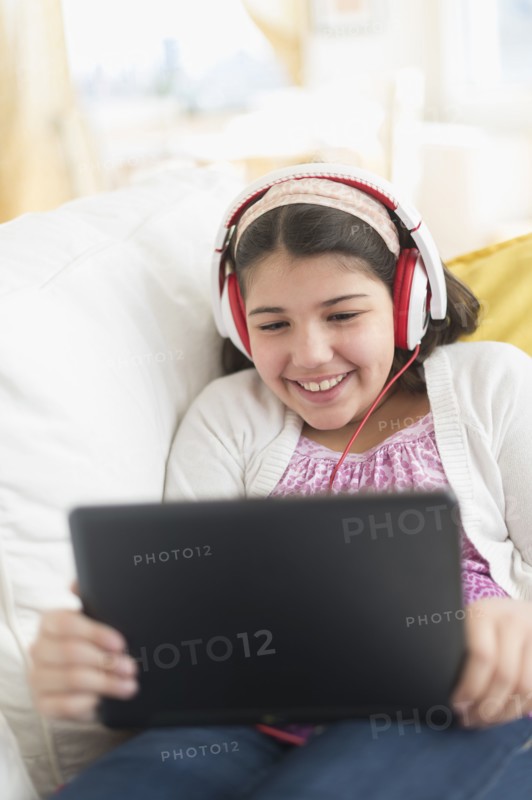 Hispanic girl using digital tablet on sofa