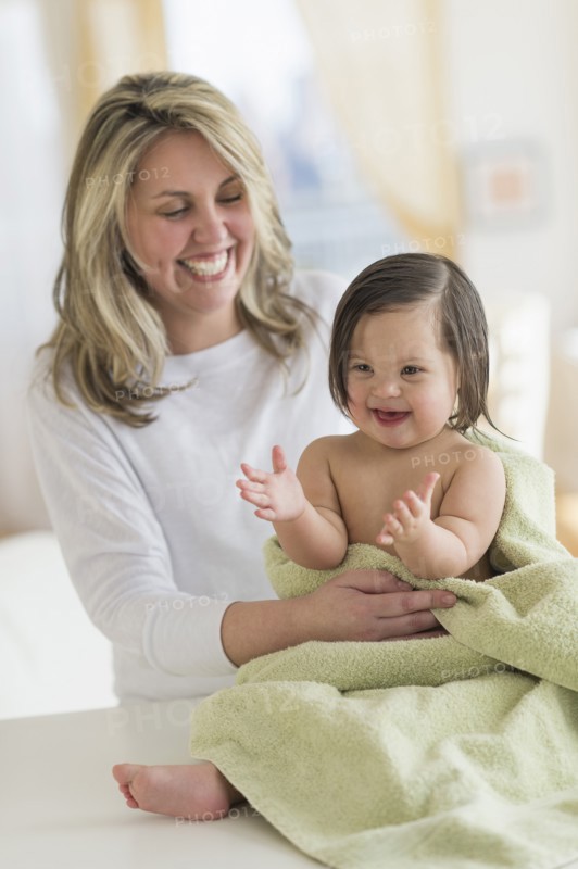Hispanic mother drying toddler daughter after bath