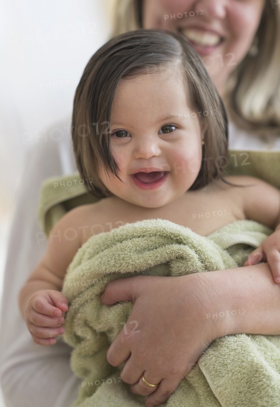 Hispanic mother drying toddler daughter after bath