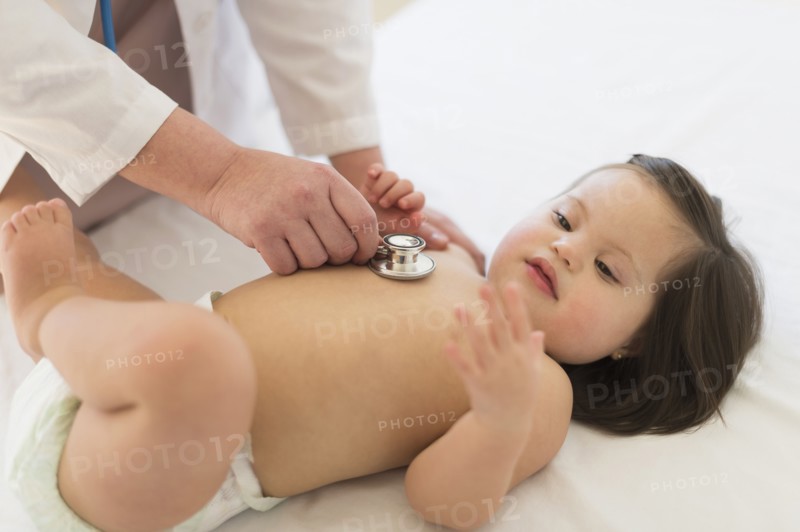 Hispanic doctor listening to toddler's heartbeat