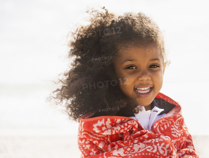 Mixed race girl wrapped in towel on beach