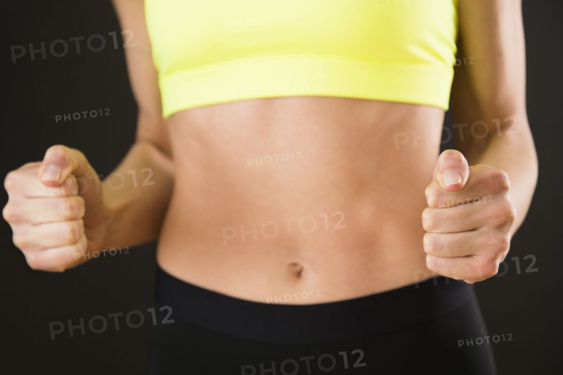 Caucasian woman with bare stomach clenching her fists