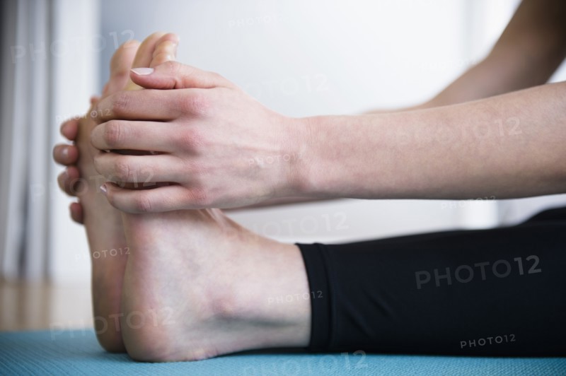 Caucasian woman stretching legs on yoga mat