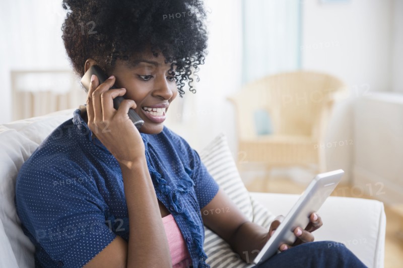 Black woman on phone using tablet computer