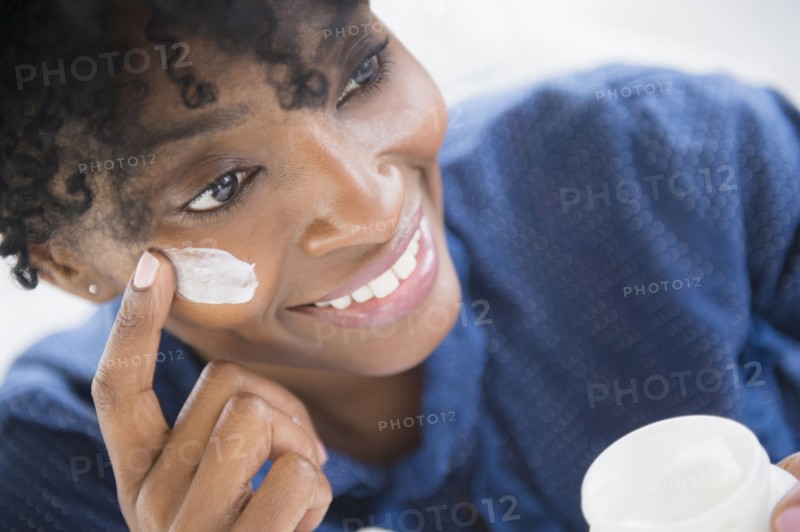 Black woman applying lotion to her cheek