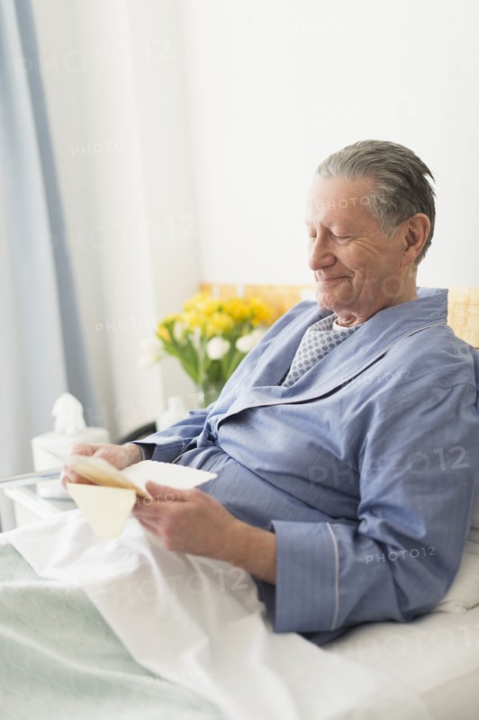 Senior Caucasian man reading in hospital bed