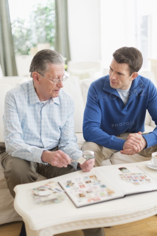 Caucasian father and son examining stamp collection