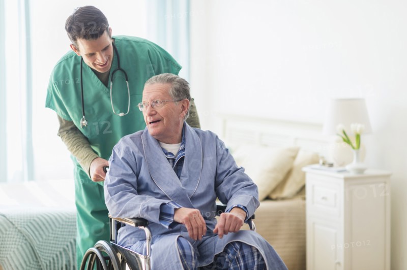 Caucasian nurse wheeling patient in home