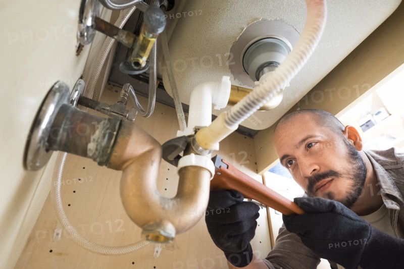 Hispanic plumber working under sink