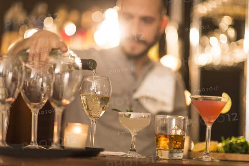 Hispanic bartender pouring drinks at bar