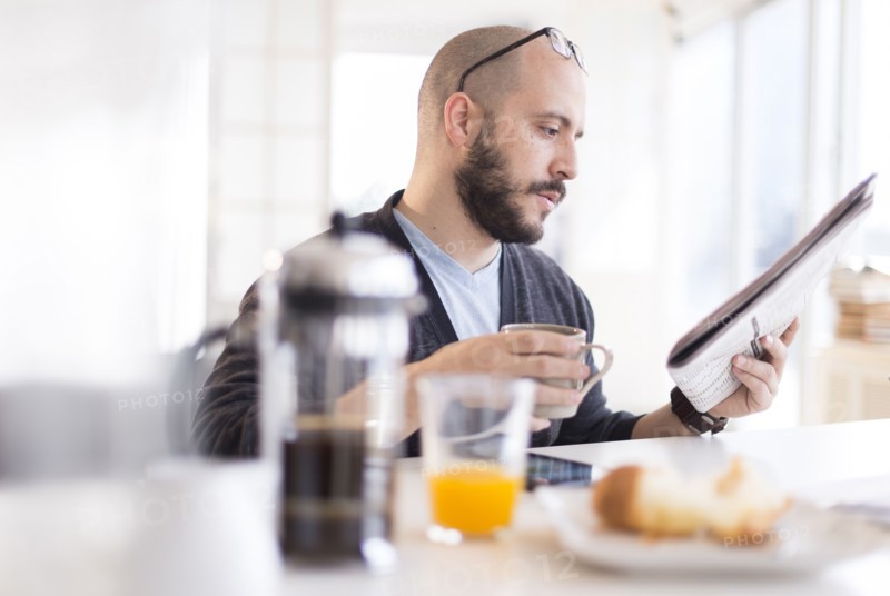 Hispanic man reading newspaper at breakfast