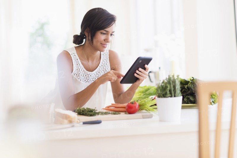 Hispanic woman cooking with digital tablet