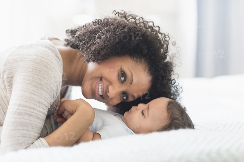 Mixed race mother playing with baby on bed