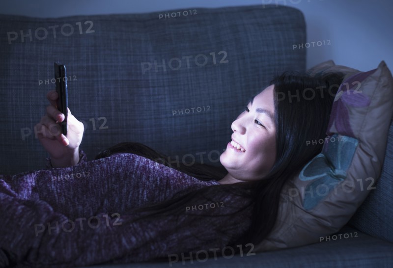 Mixed race teenage girl using cell phone on sofa