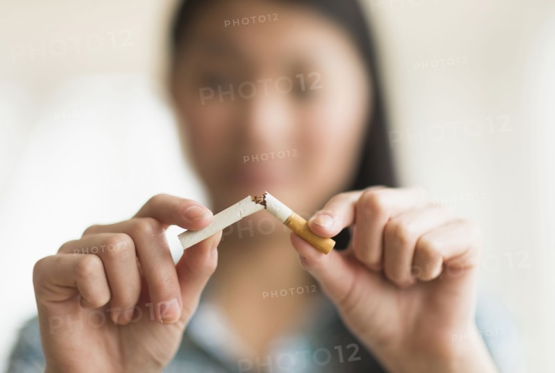Mixed race teenage girl breaking cigarette in half