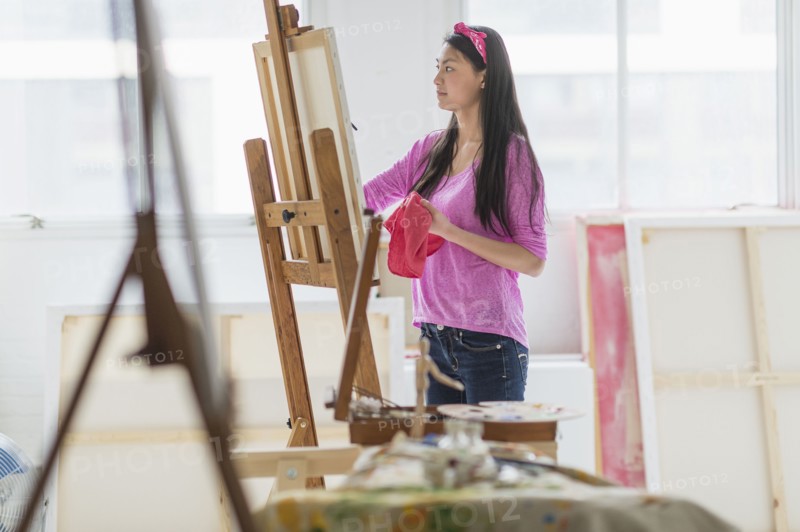 Mixed race teenage girl painting in studio