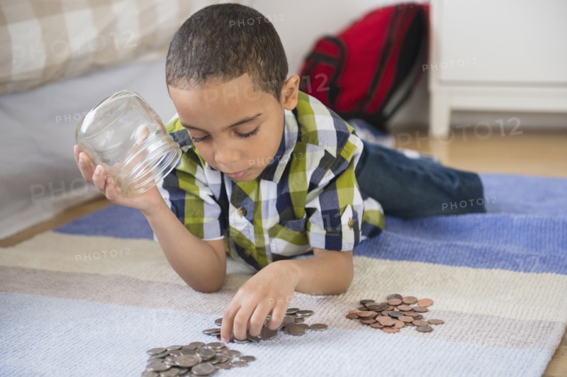 Mixed race boy counting change on floor