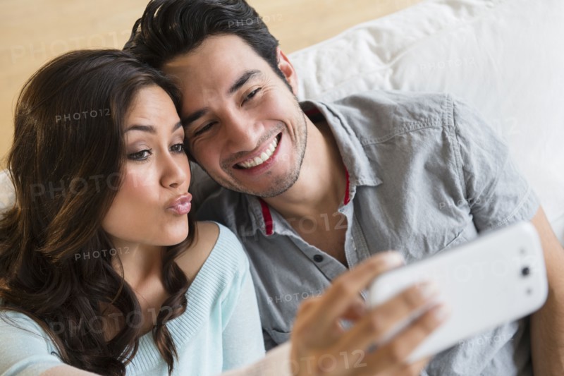 Couple taking pictures together on sofa