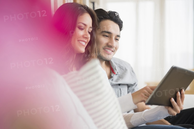 Couple using tablet computer on sofa