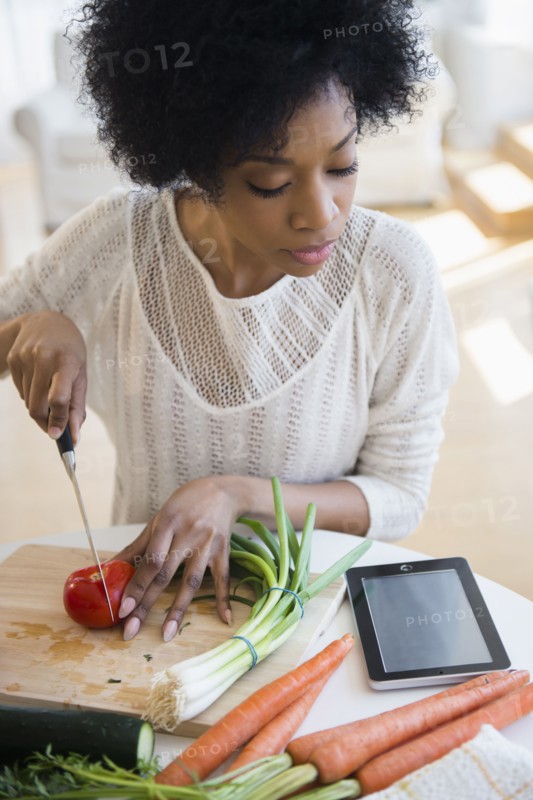 African American woman using tablet computer to cook