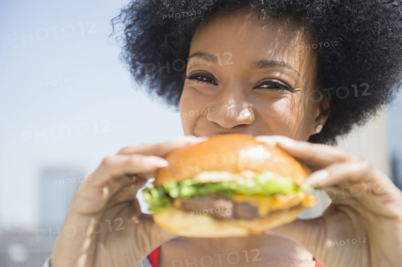 African American woman eating cheeseburger
