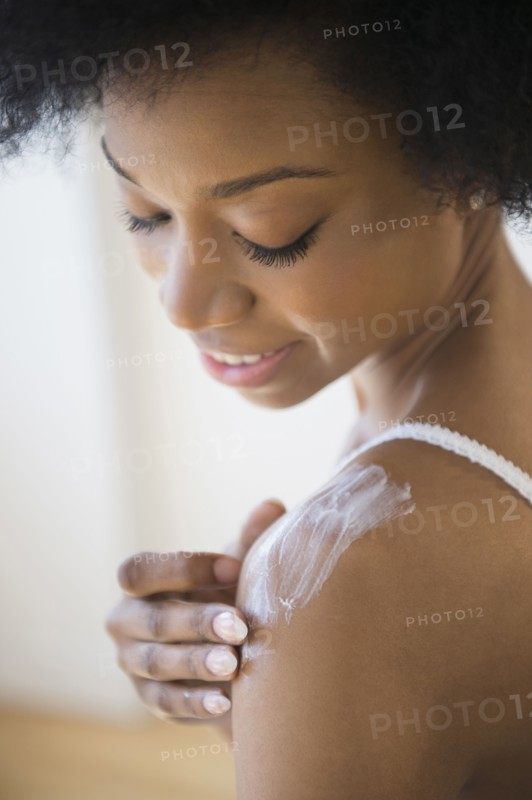 African American woman applying moisturizer