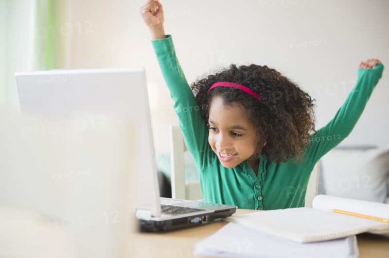 African American girl cheering at laptop