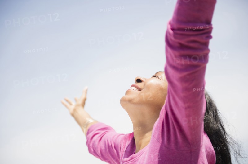 Mixed race woman with arms outstretched outdoors