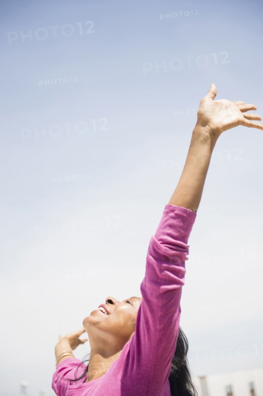 Mixed race woman with arms outstretched outdoors