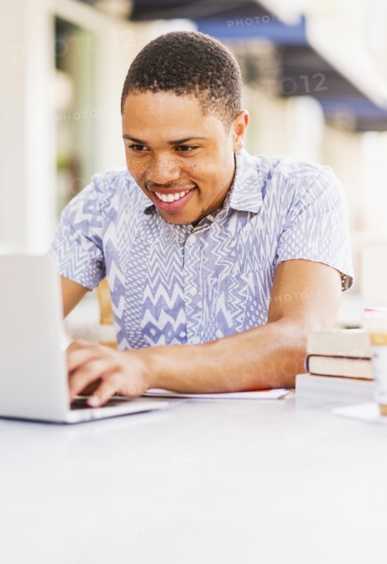 African American man using laptop at sidewalk cafe