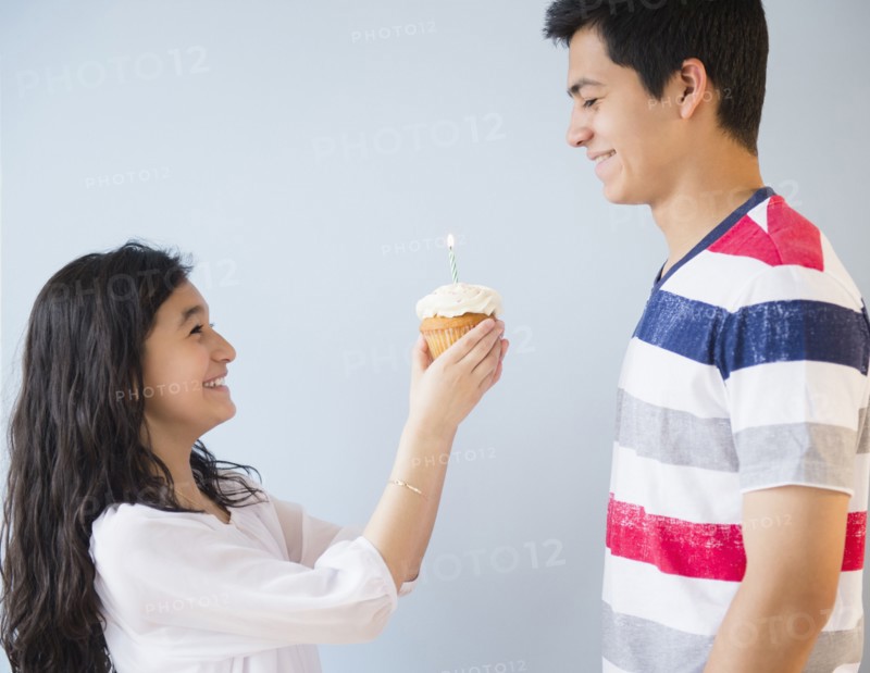 Hispanic brother and sister celebrating birthday with cupcake