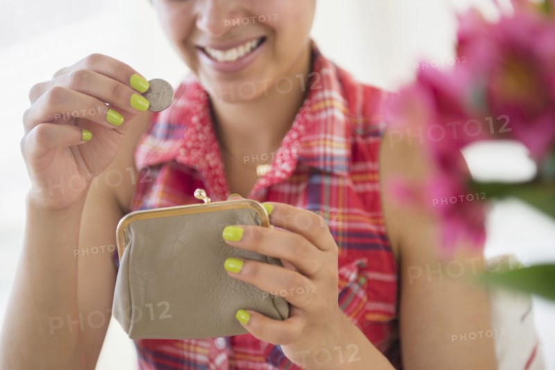 Mixed race woman putting coin into purse