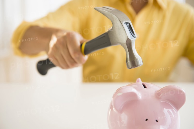 Close up of mixed race man holding hammer over piggy bank