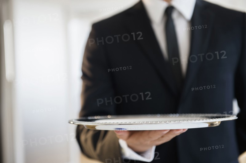 Close up of mixed race waiter holding empty tray