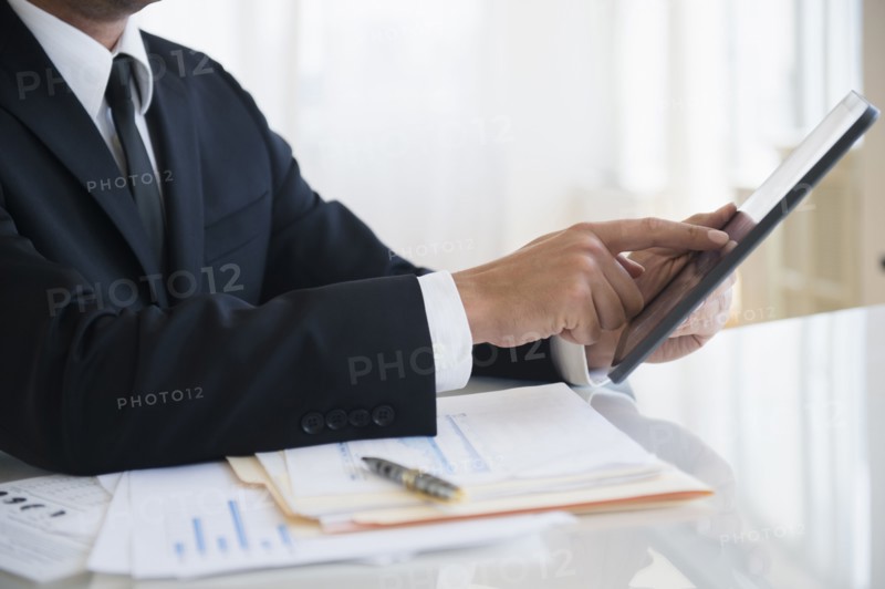 Close up of mixed race businessman using digital tablet at office desk