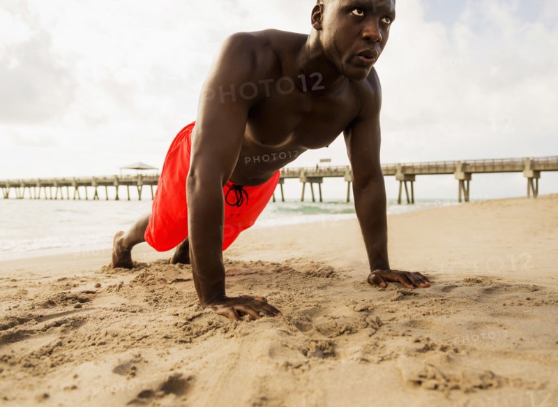 Mixed race man doing push ups on beach
