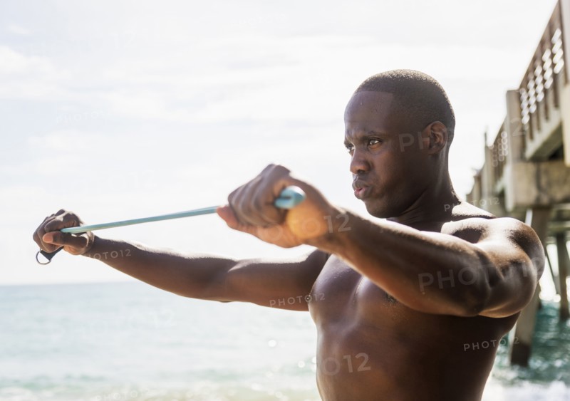 Mixed race man using resistance band on beach