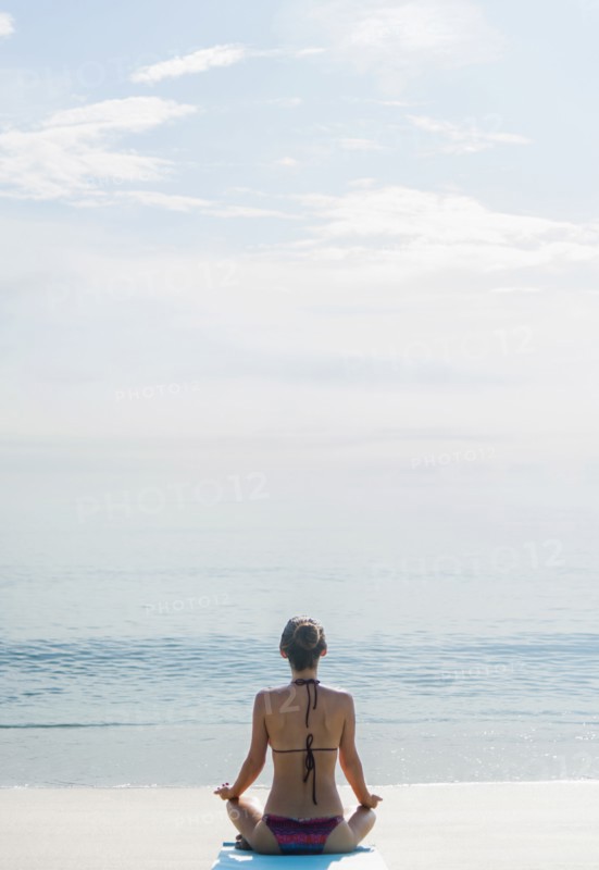 Caucasian woman meditating on beach