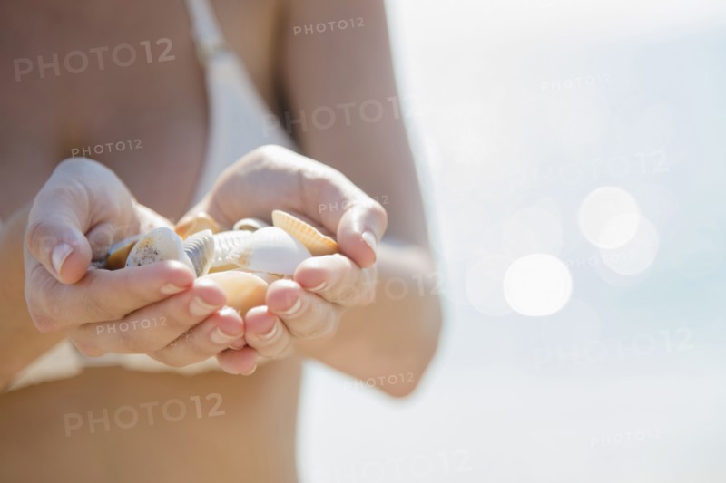 Close up of Caucasian woman holding seashells at beach