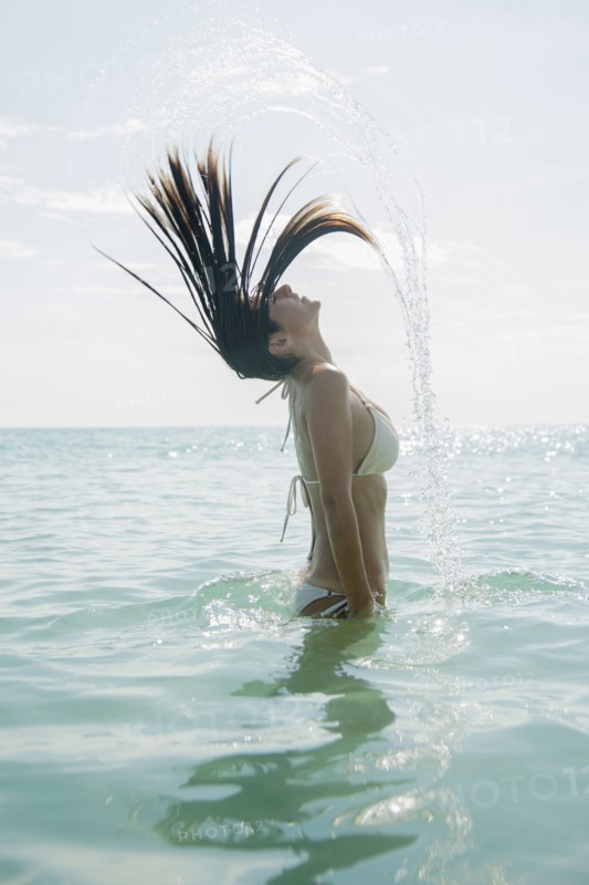 Caucasian woman splashing hair in ocean
