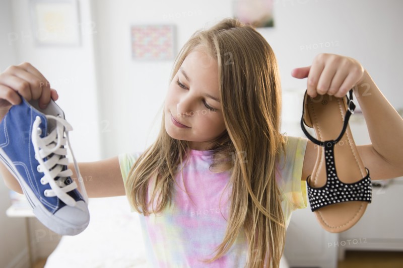 Caucasian girl picking shoes in bedroom