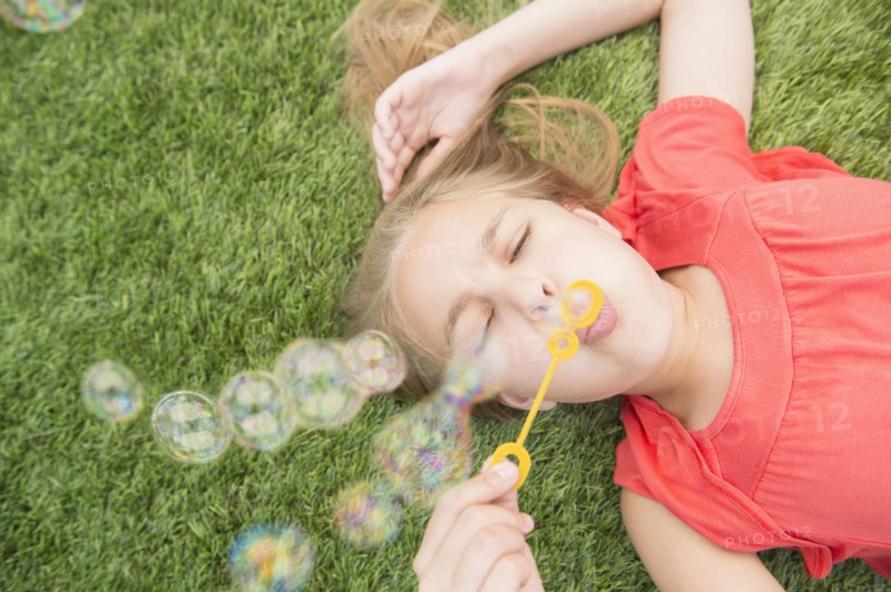 Caucasian girl blowing bubbles on grassy lawn