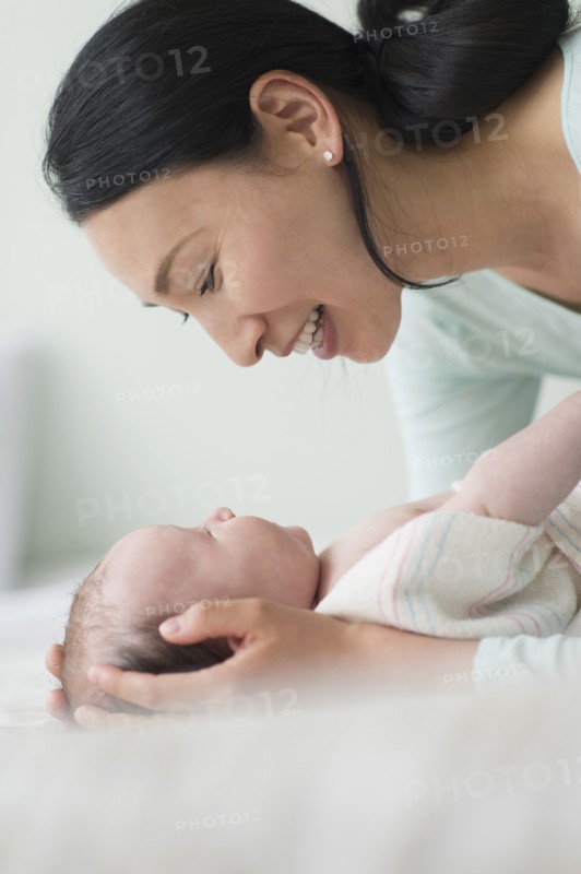Asian mother holding baby on bed