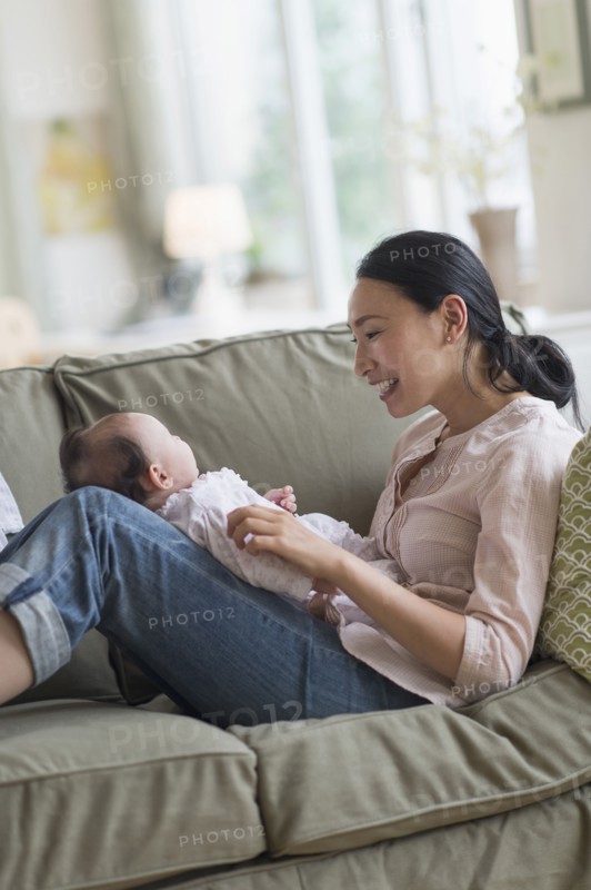 Asian mother playing with baby in living room