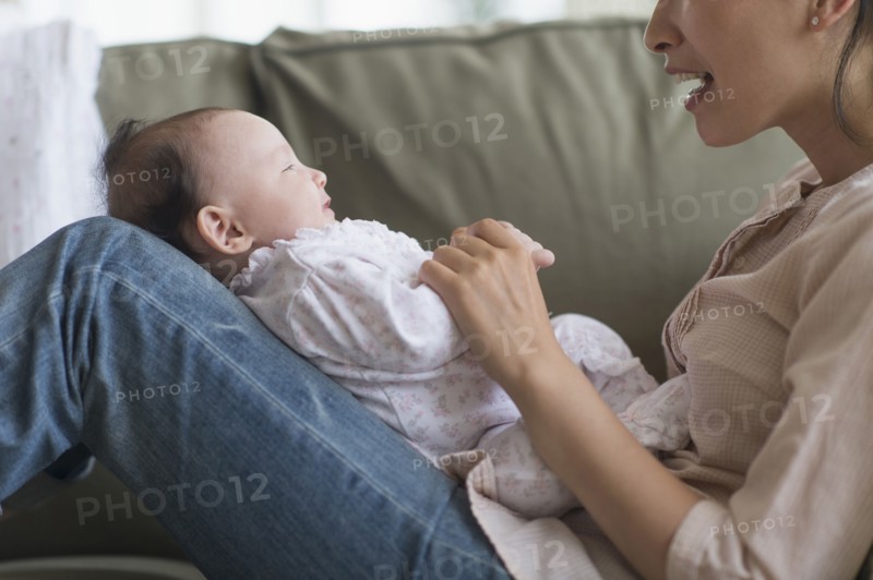 Asian mother playing with baby in living room