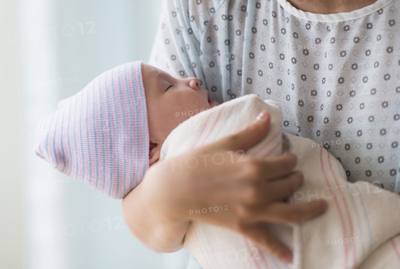 Asian mother holding newborn baby in hospital