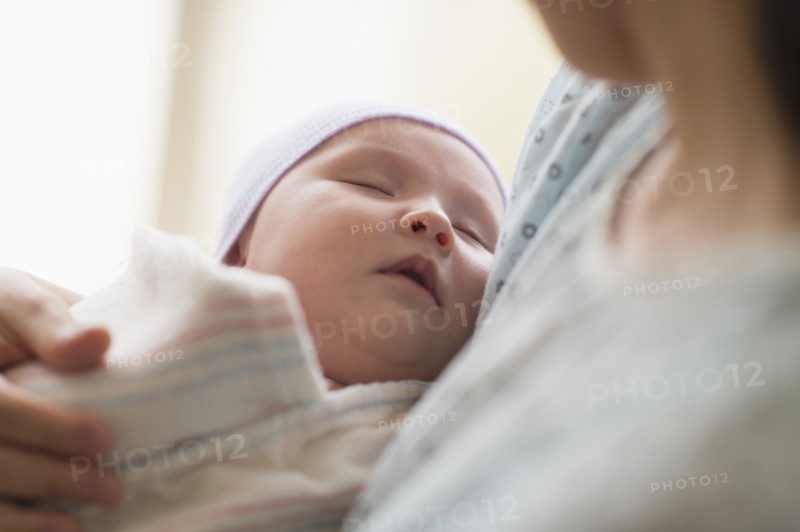 Asian mother holding newborn baby in hospital