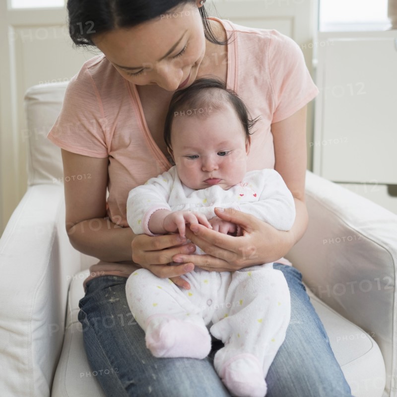 Asian mother playing with baby in living room