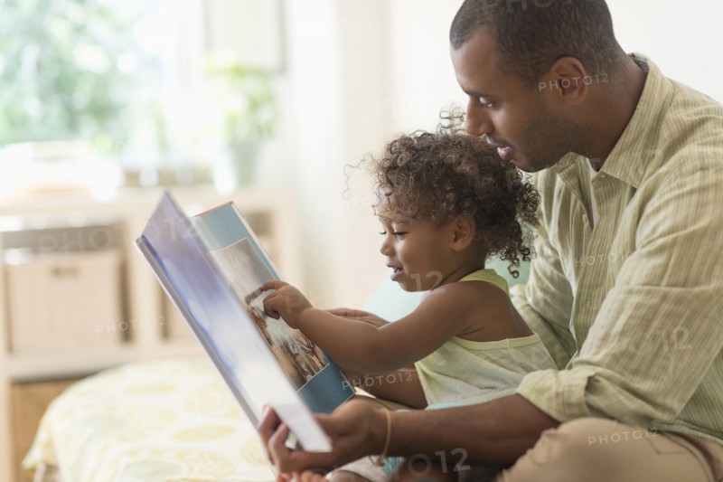 Father and daughter reading book on bed