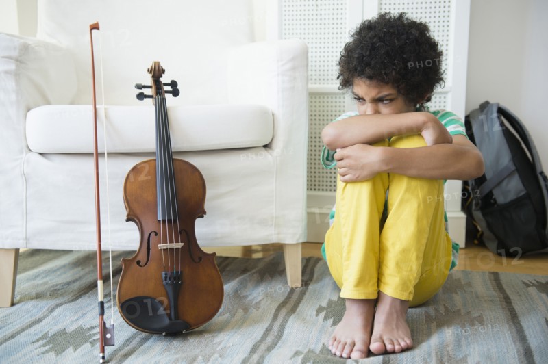 Angry mixed race boy refusing to practice violin